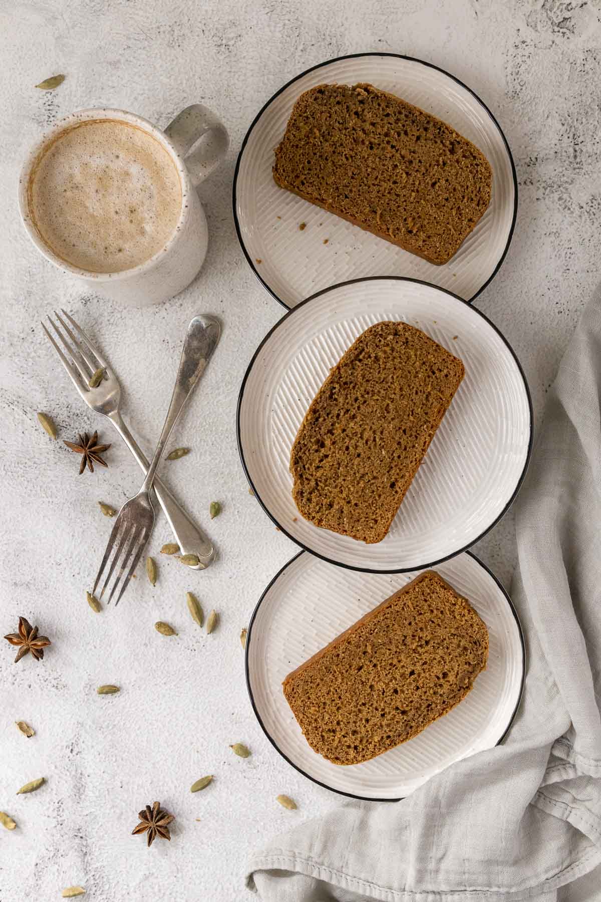 Sliced ontbitjkoek on plates with a cup of coffee.