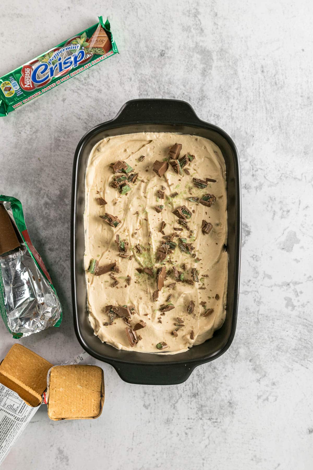 Step 4.2 - Caramel cream layered on top of the tennis biscuits and then topped with some pieces of peppermint crisp.
