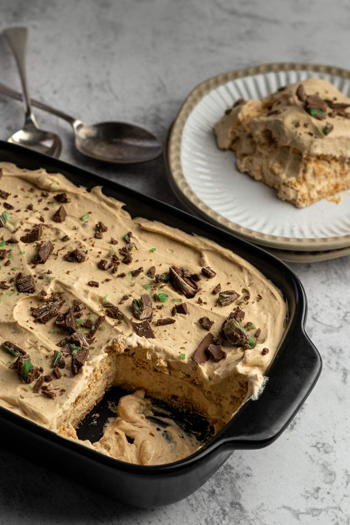 Serving of peppermint crisp tart in a plate next to the tart dish.