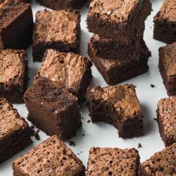 Chocolate brownies spread out on baking parchment.