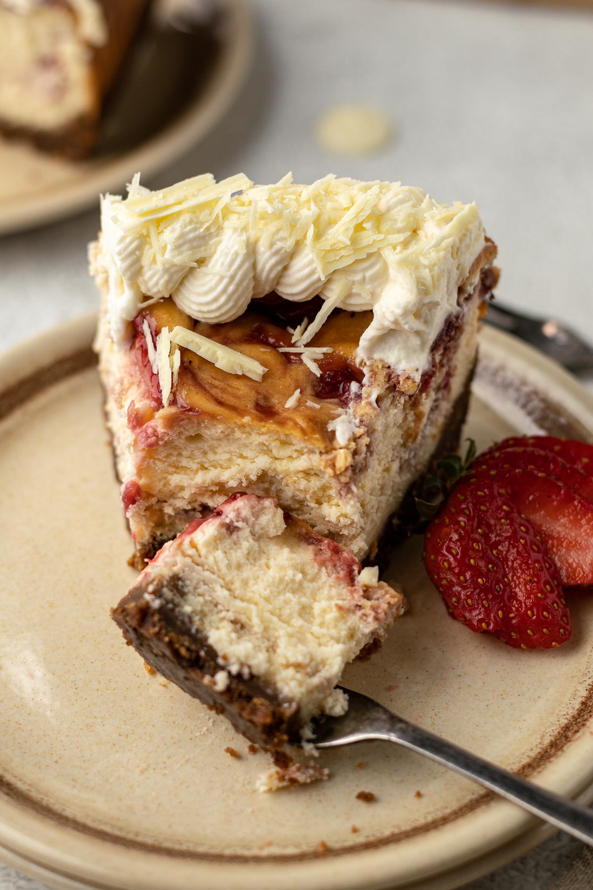 Slice of strawberry white chocolate cheesecake with a piece on a cake fork