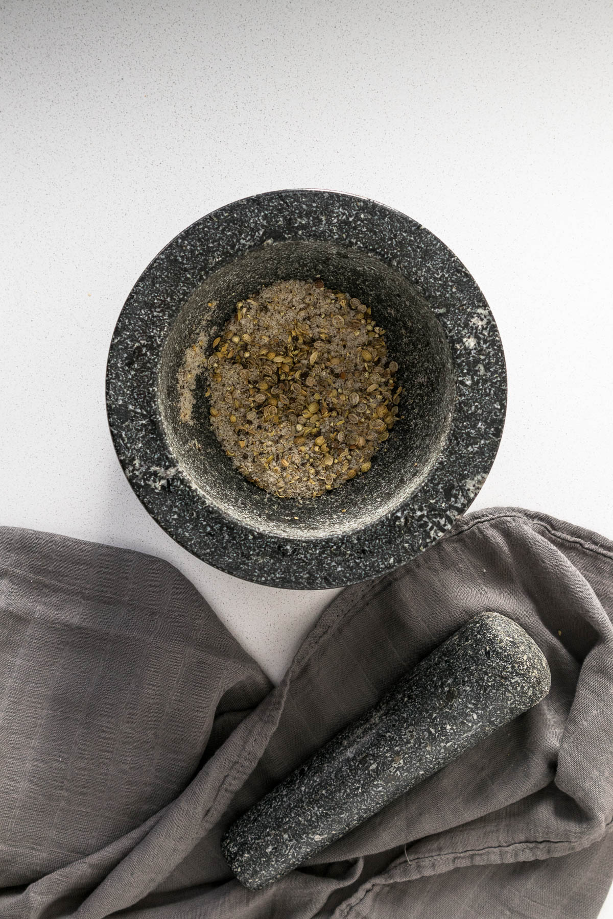 Crushed coriander seeds in a mortar bowl.