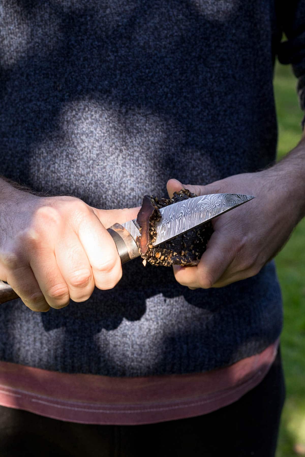 Close up of man slicing biltong for snacking.