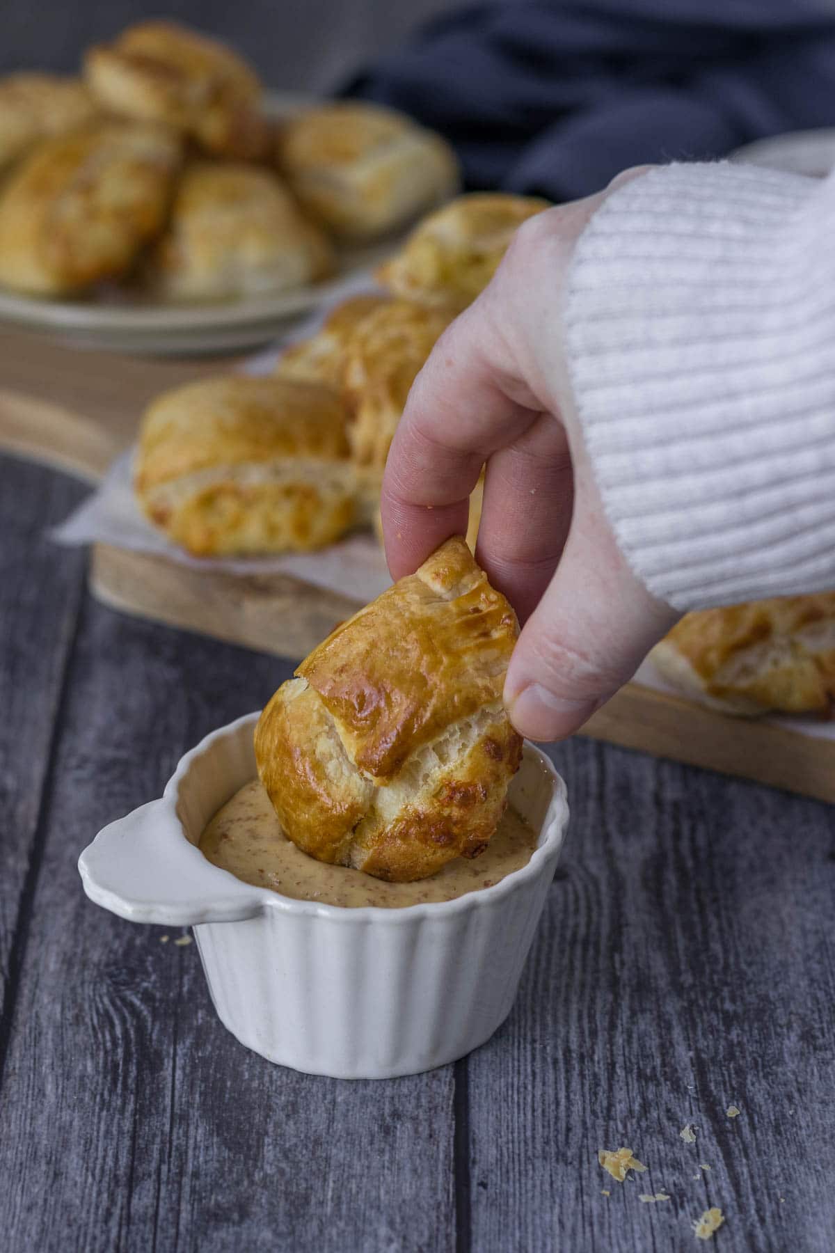 Cheese roll being dipped into wholegrain mustard.