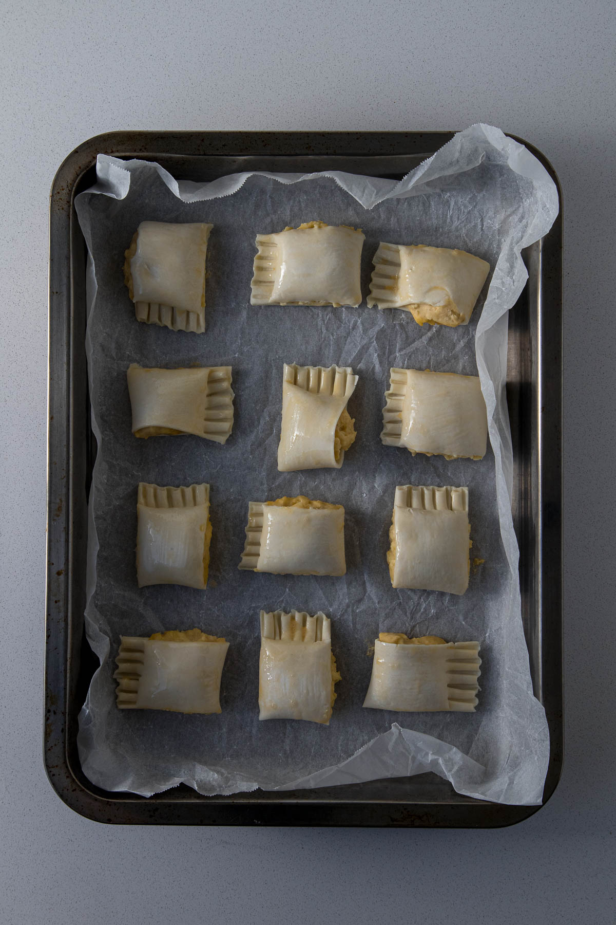 Cheese rolls in a baking tray and brushed with a beaten egg.