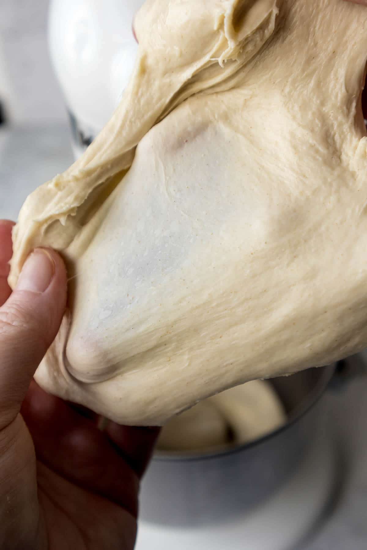 Hand stretching the dough to show the window-pane test.