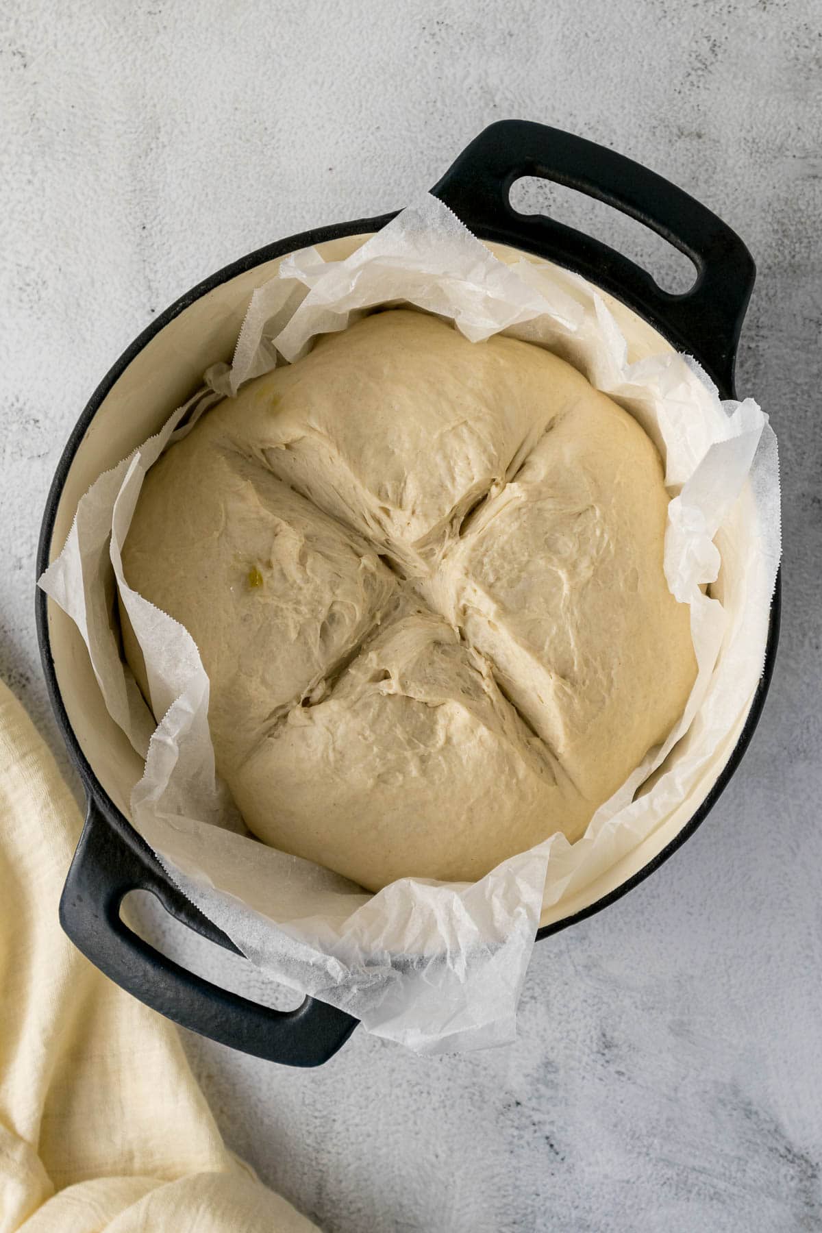 Scored bread dough in a pot.