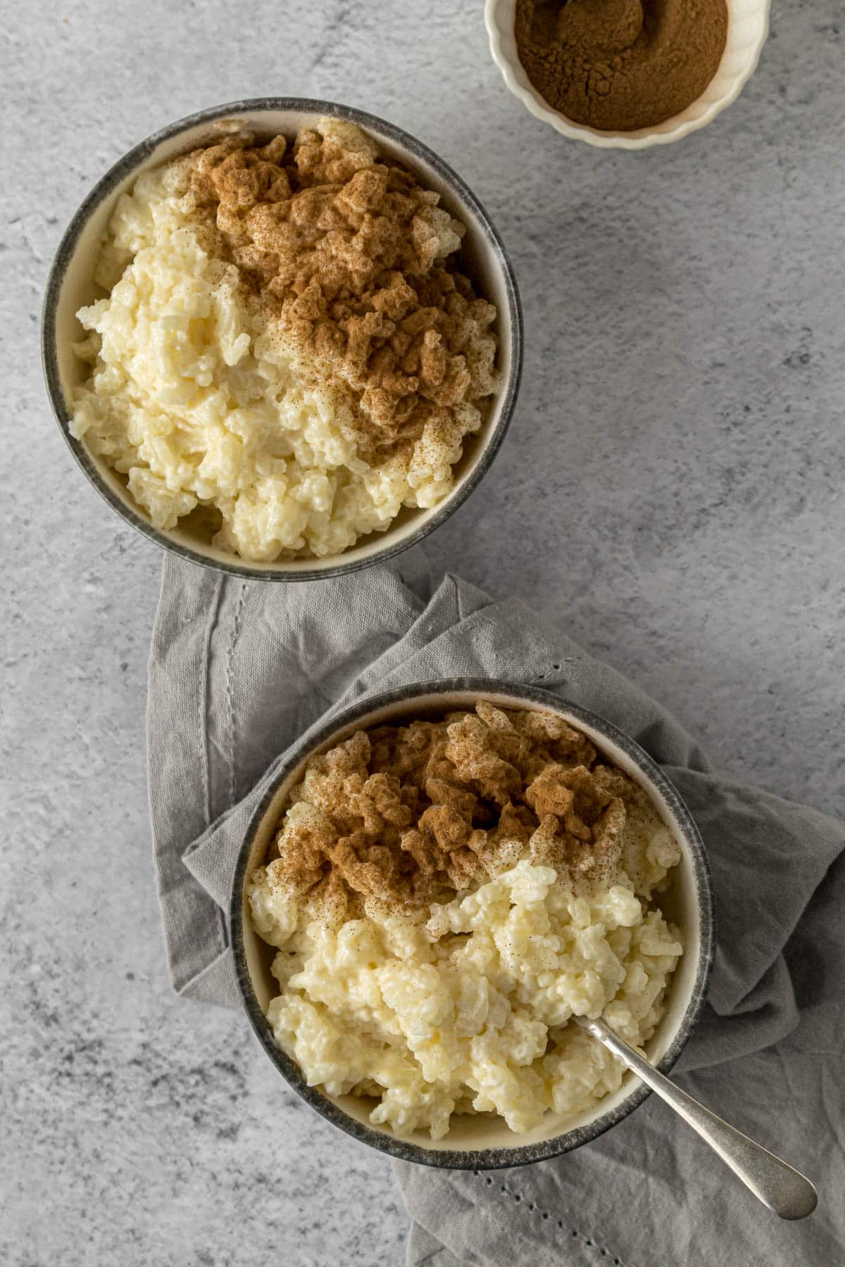 Vanilla rice pudding in bowls topped with ground cinnamon.