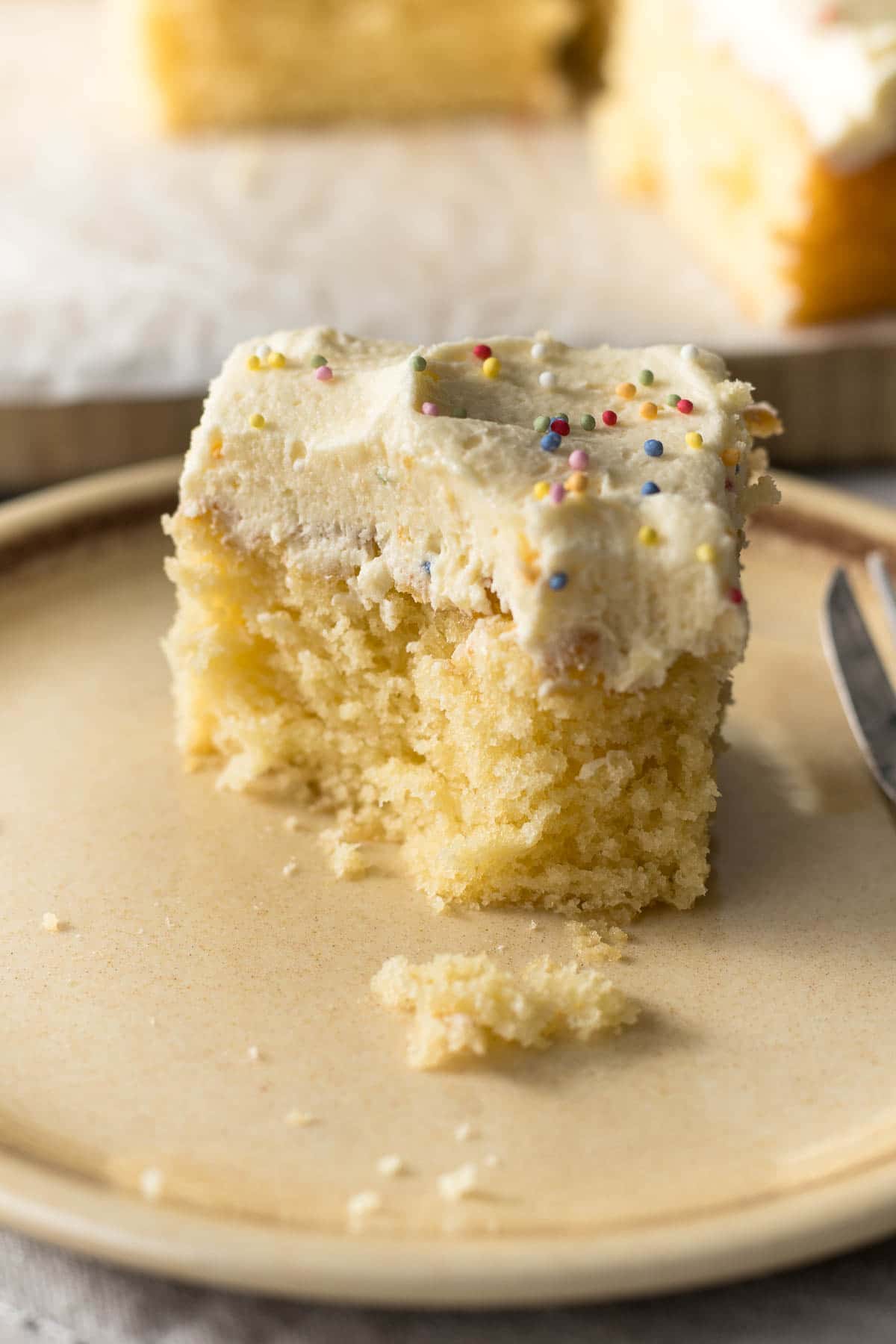 Slice of vanilla traybake on a plate.