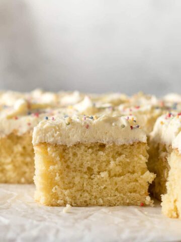 Sliced vanilla traybake showing vanilla buttercream frosting and sprinkles.