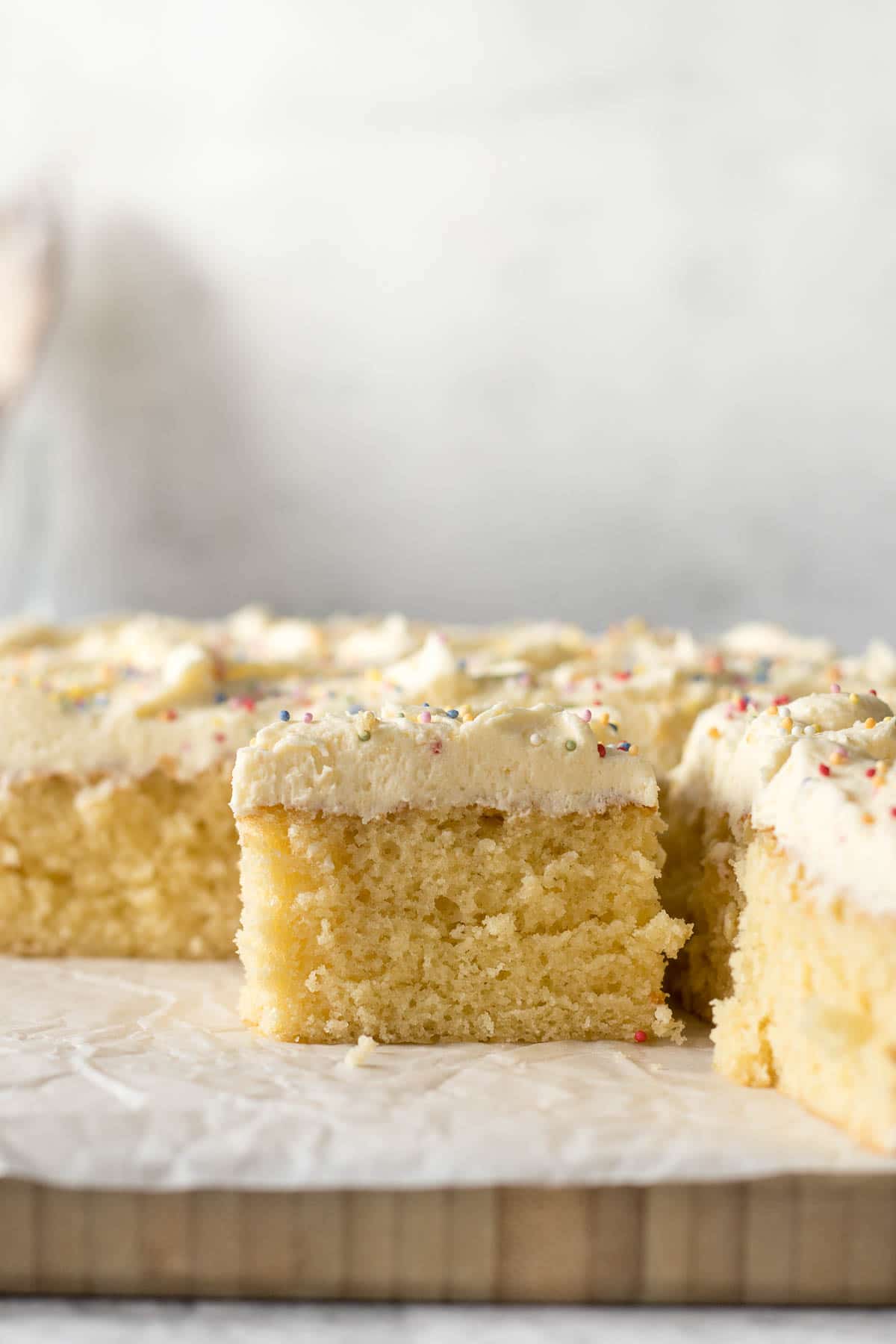Sliced vanilla traybake showing vanilla buttercream frosting and sprinkles.