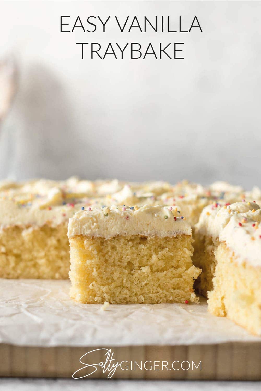 Sliced vanilla traybake showing vanilla buttercream frosting and sprinkles.