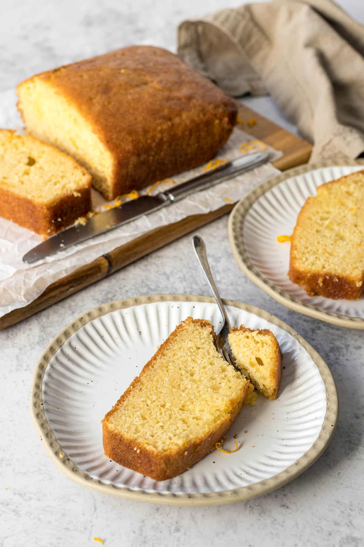 Sliced orange loaf cake on a plate.