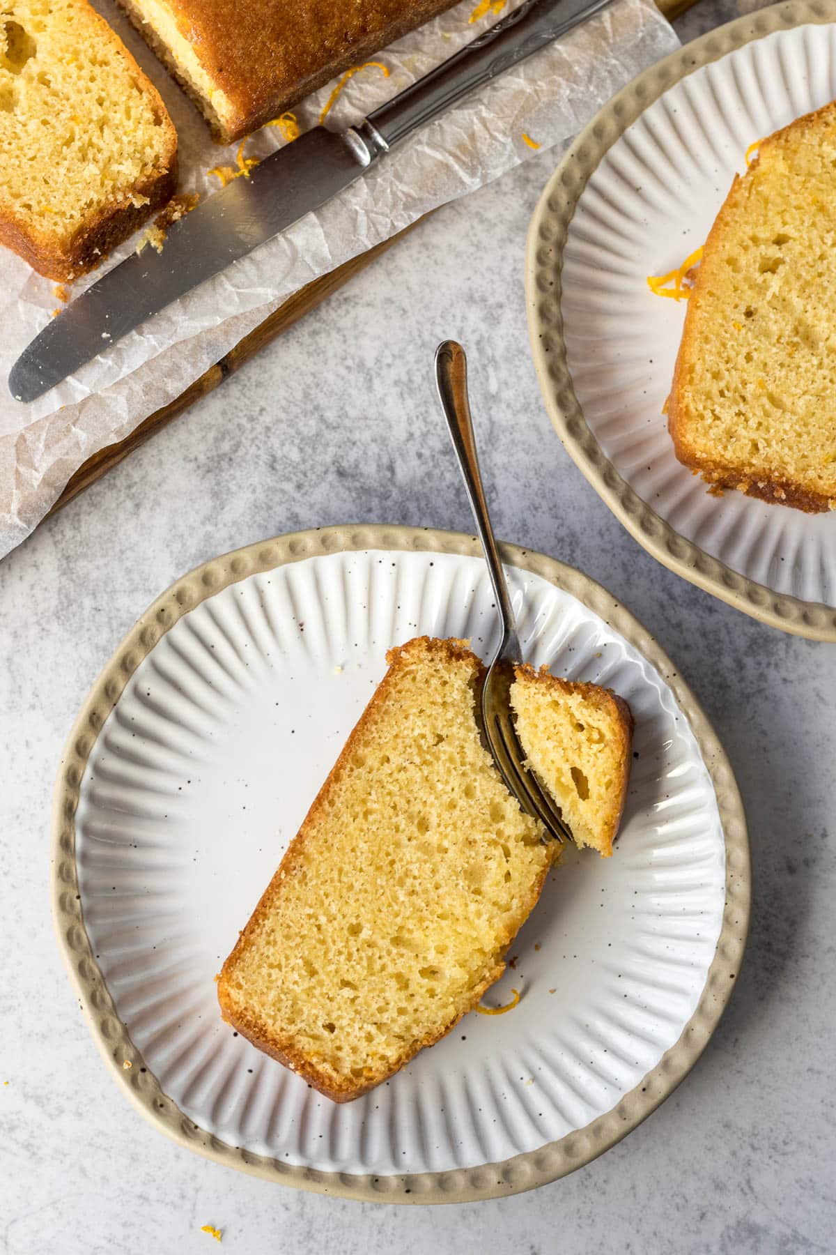 Sliced orange loaf cake on a plate.