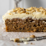 Sliced carrot cake tray bake with cream cheese frosting.