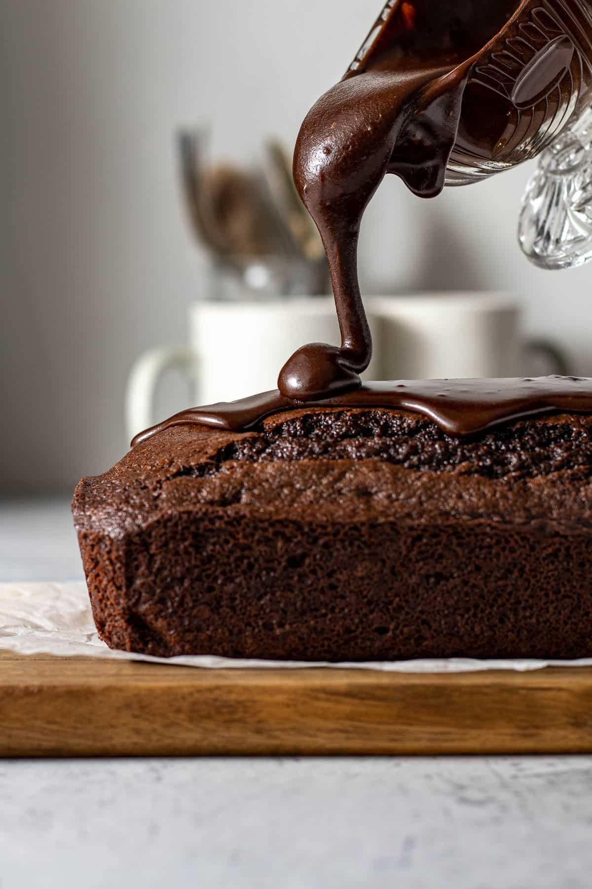 Glaze being poured onto chocolate loaf cake.