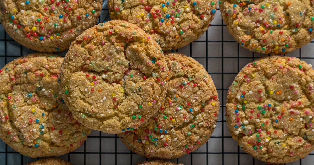 Sugar cookies with sprinkles on a cooling rack.