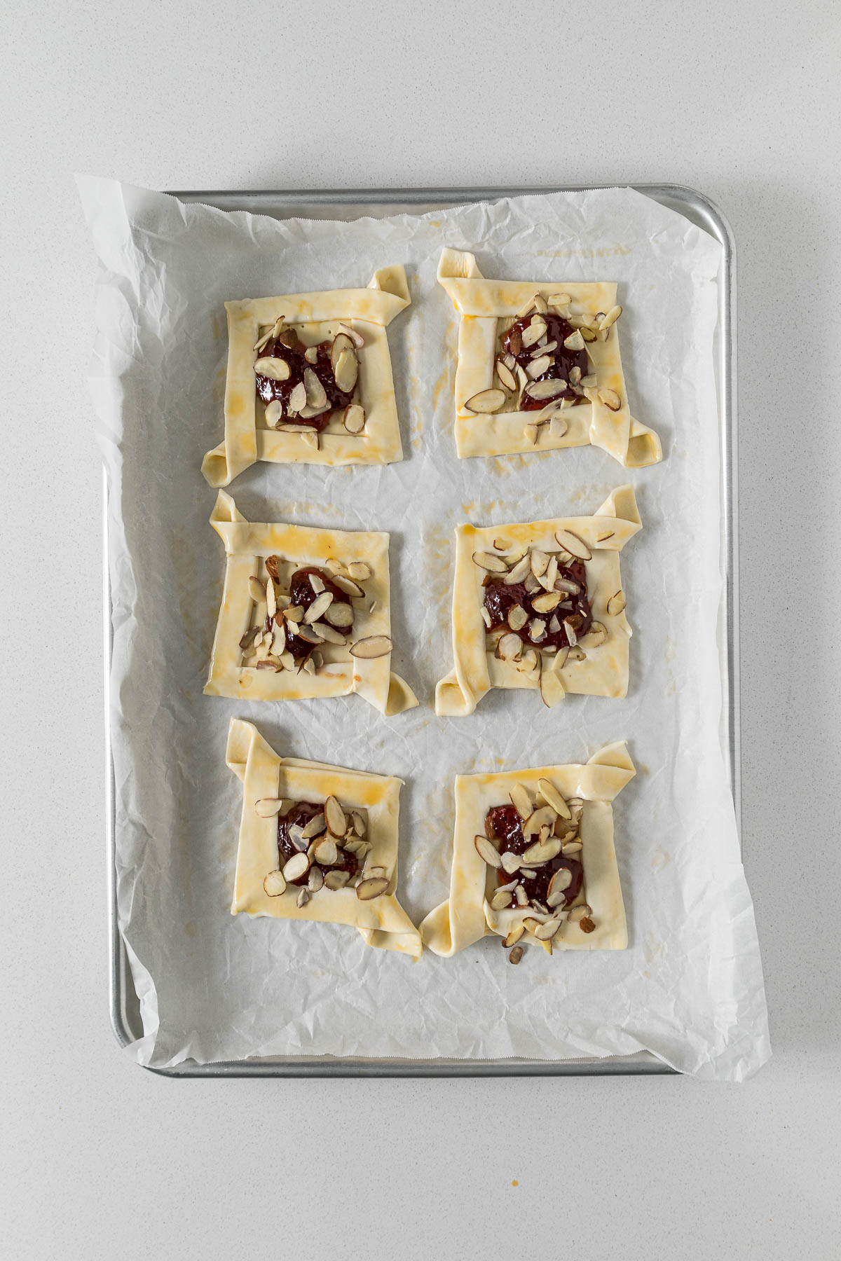 Step 8 - Edges of pastry brushed with egg basting and topped with sliced almonds.