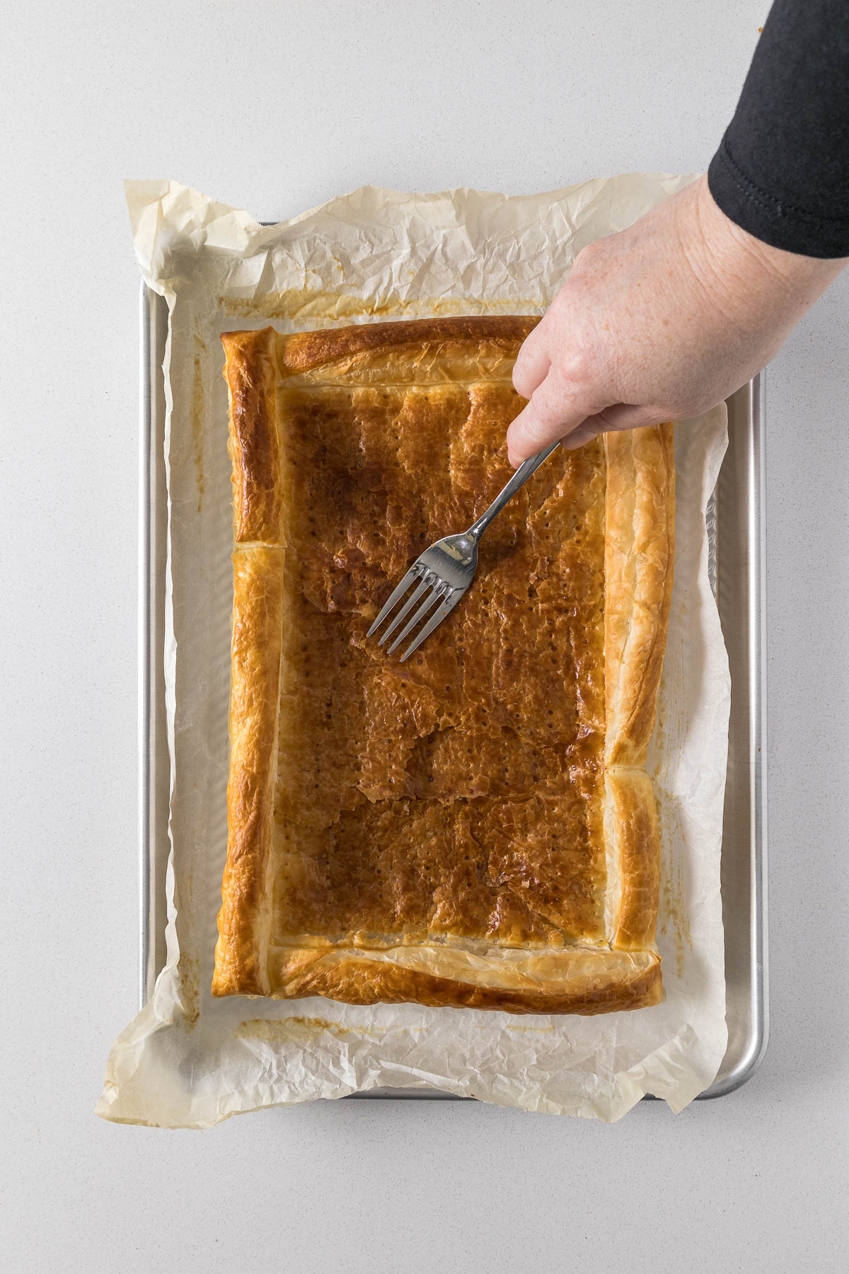 Step 10 - Baker pressing down the centre of the pastry with a fork.
