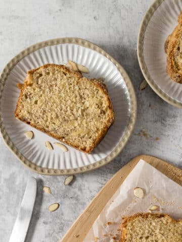 Slice of banana bread with almonds on a plate.