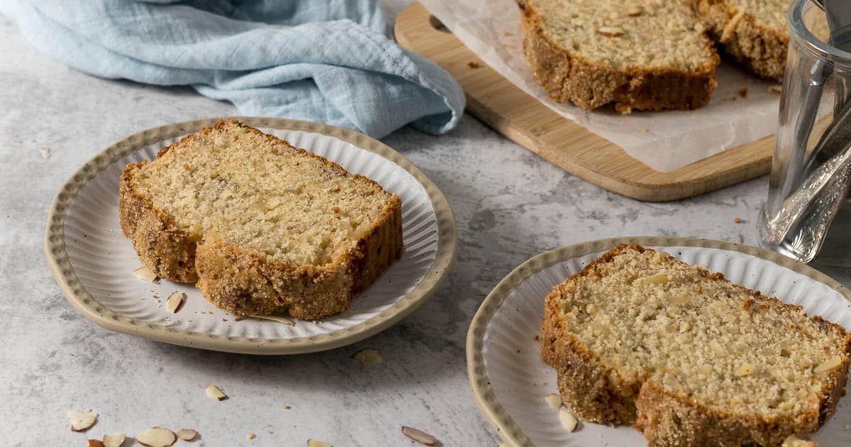 Slice of banana bread with almonds on a plate.