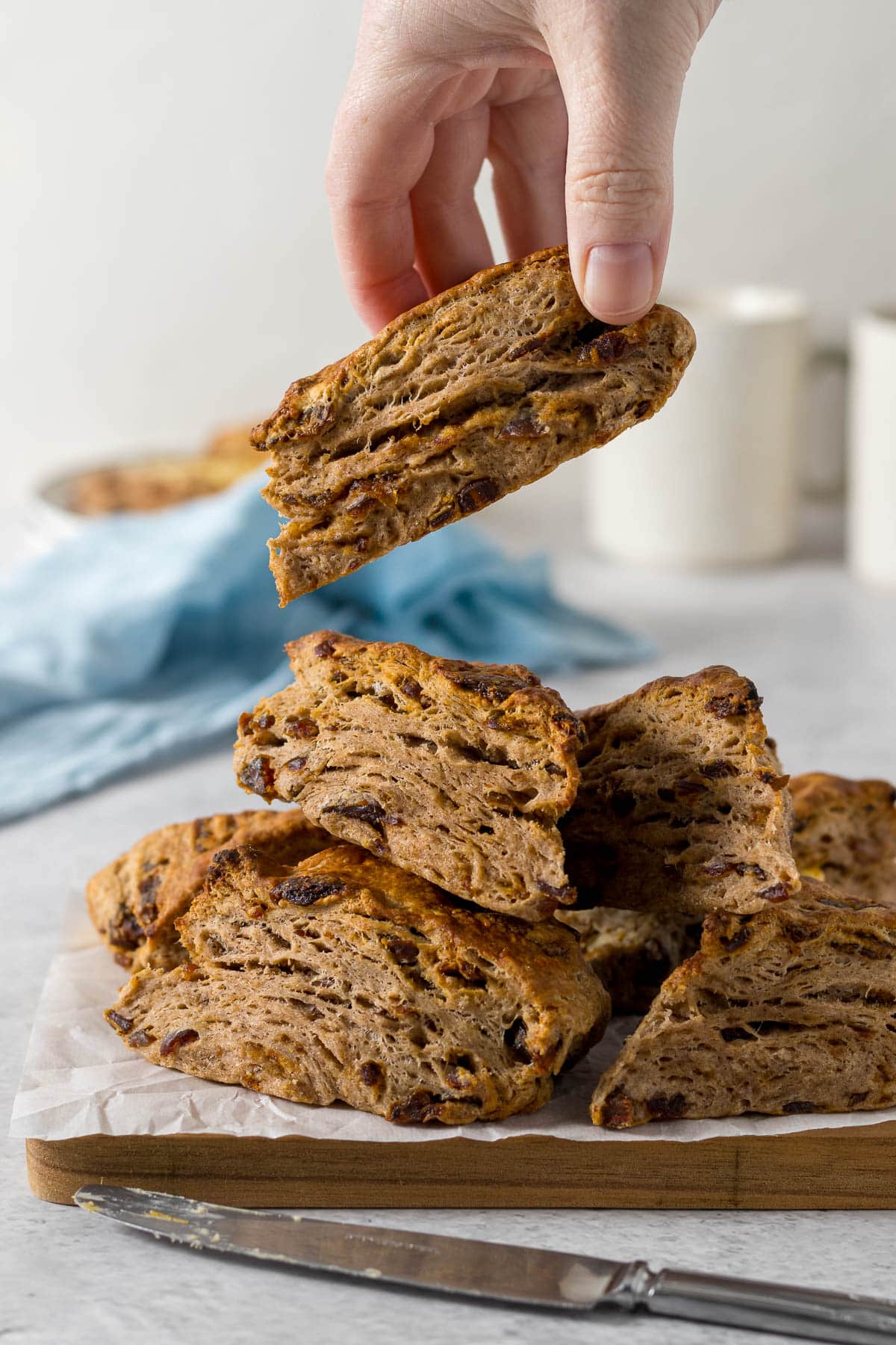 Hand picking up a date scone from a pile of scones on a platter.