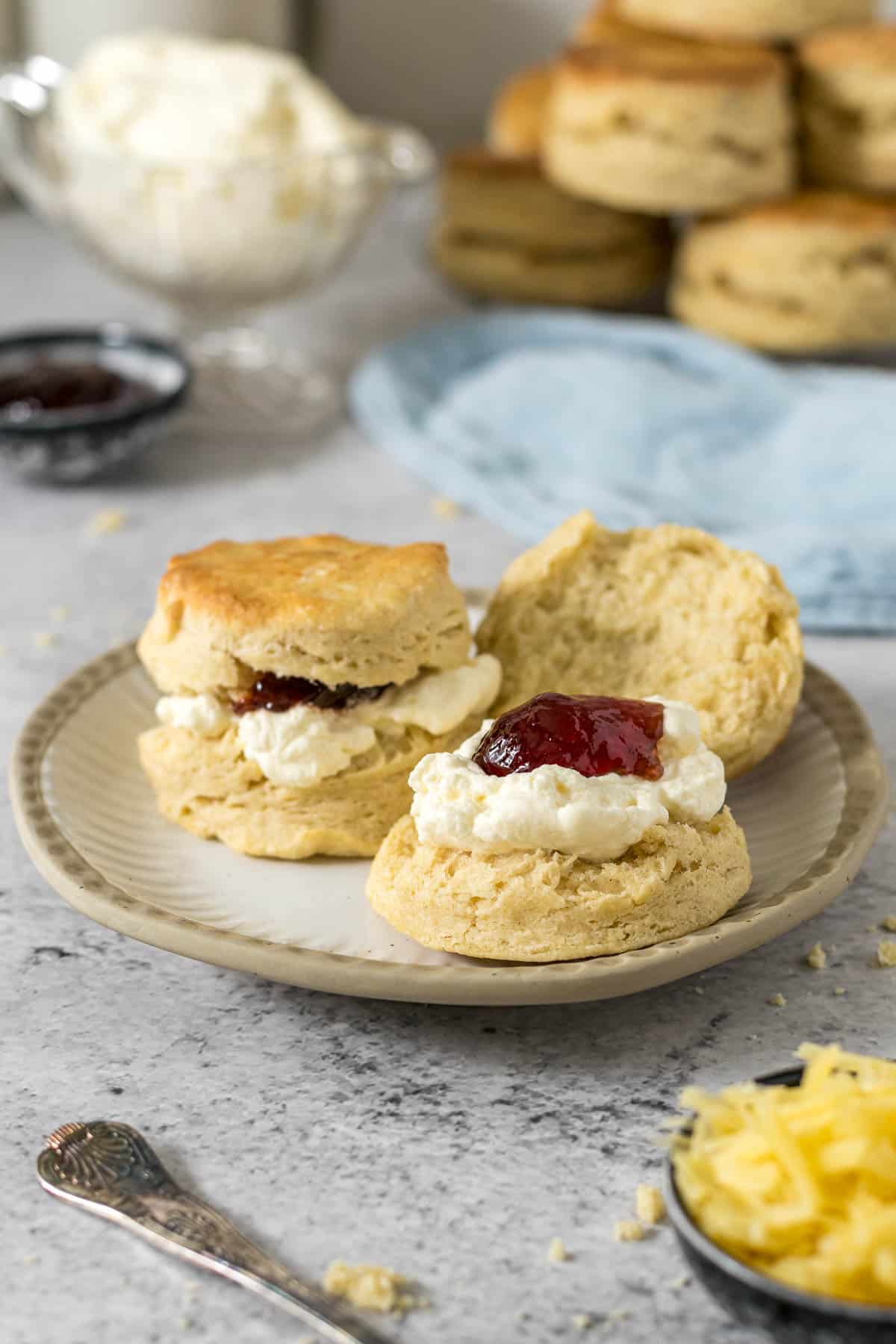 Scones topped with cream and jam on a plate.
