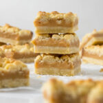 Three tan squares stacked on each other showing the layers of shortbread and caramel.