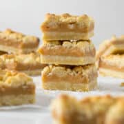 Three tan squares stacked on each other showing the layers of shortbread and caramel.