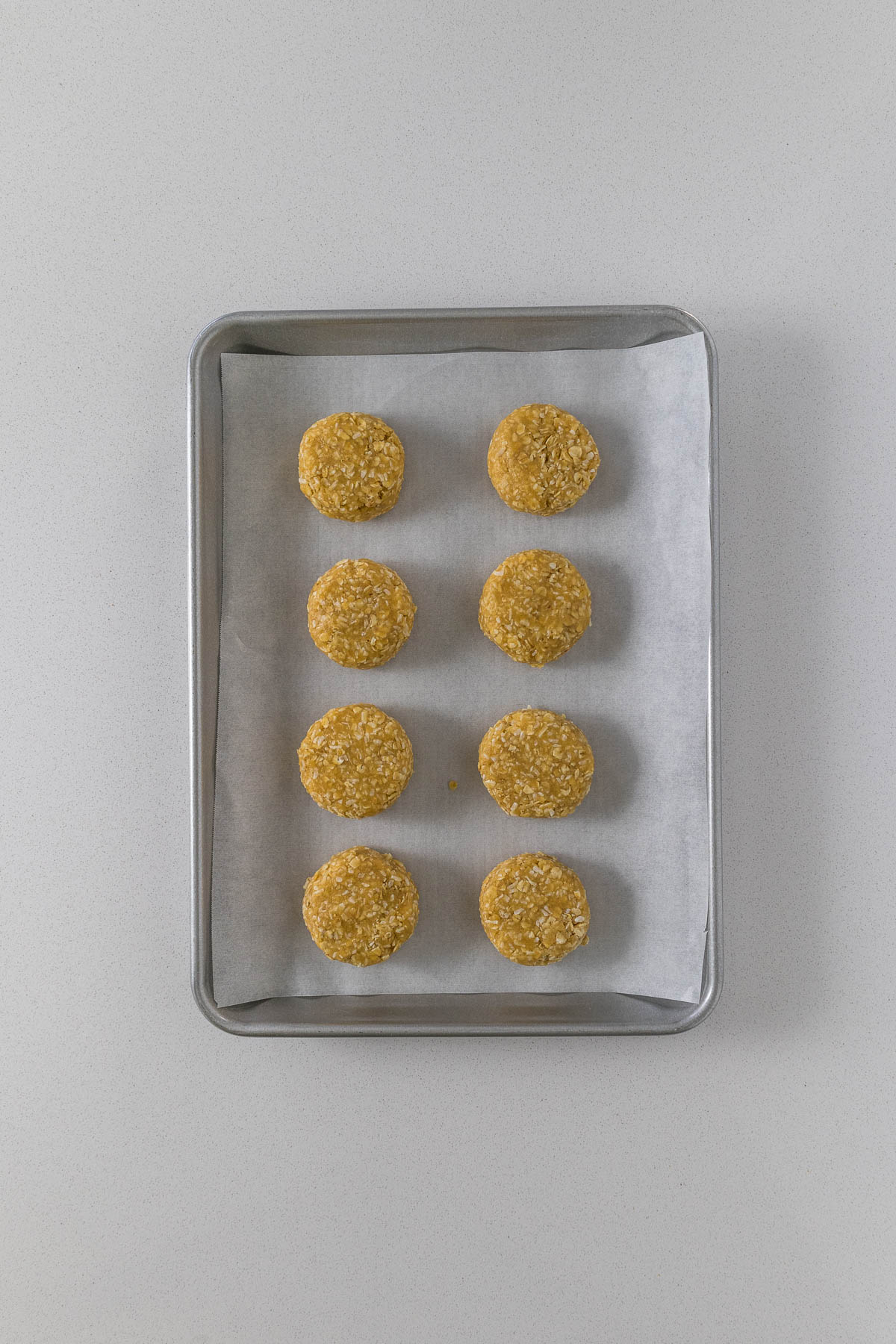 Step 6 - Rolled and flattened ANZAC biscuits on a baking tray.