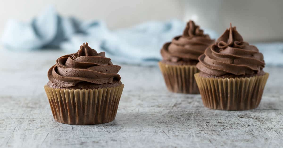 Three chocolate cupcakes with a chocolate buttercream swirl.