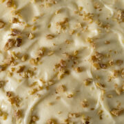 Cream cheese frosting sprinkled with walnut pieces.