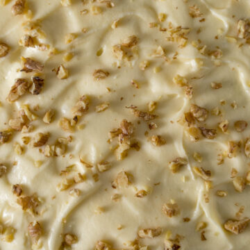 Cream cheese frosting sprinkled with walnut pieces.