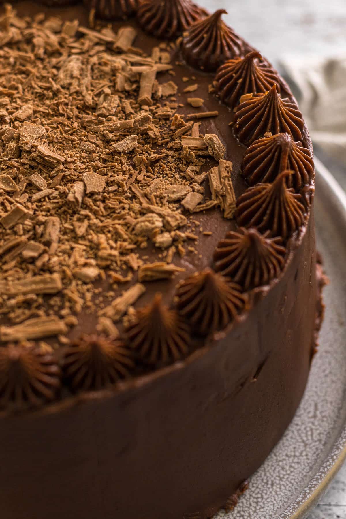 Chocolate cake with cream cheese frosting topped with flakey chocolate.