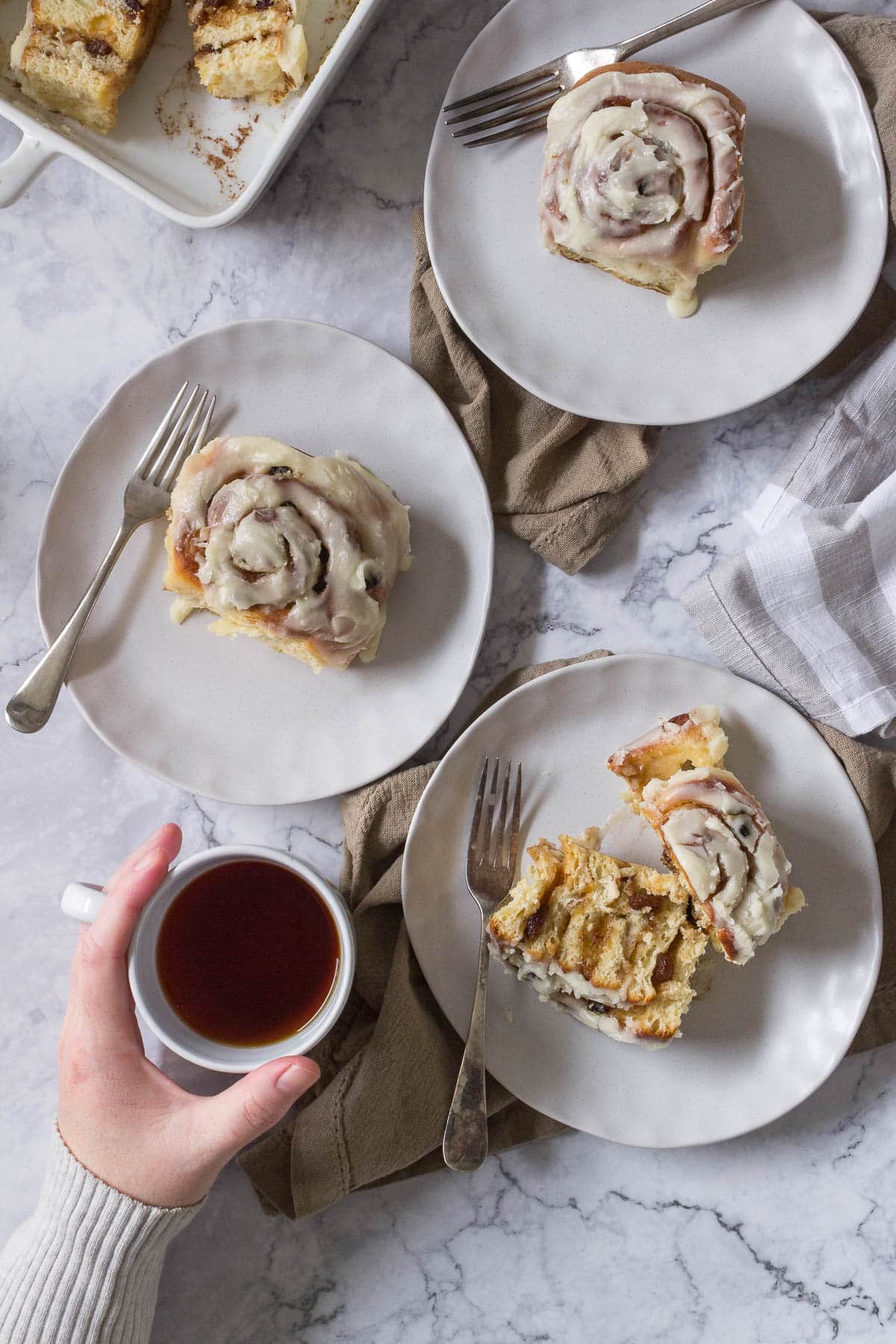 Chelsea buns on plates with a cup of tea.