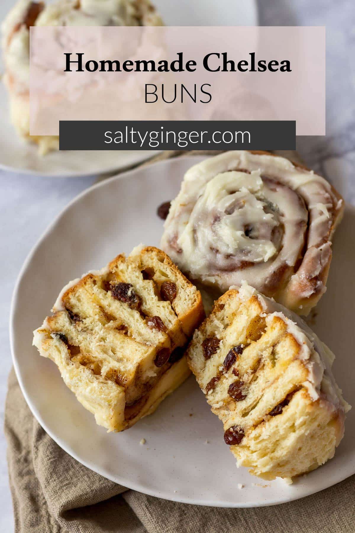 Pin - A Chelsea bun sliced in half on a plate.