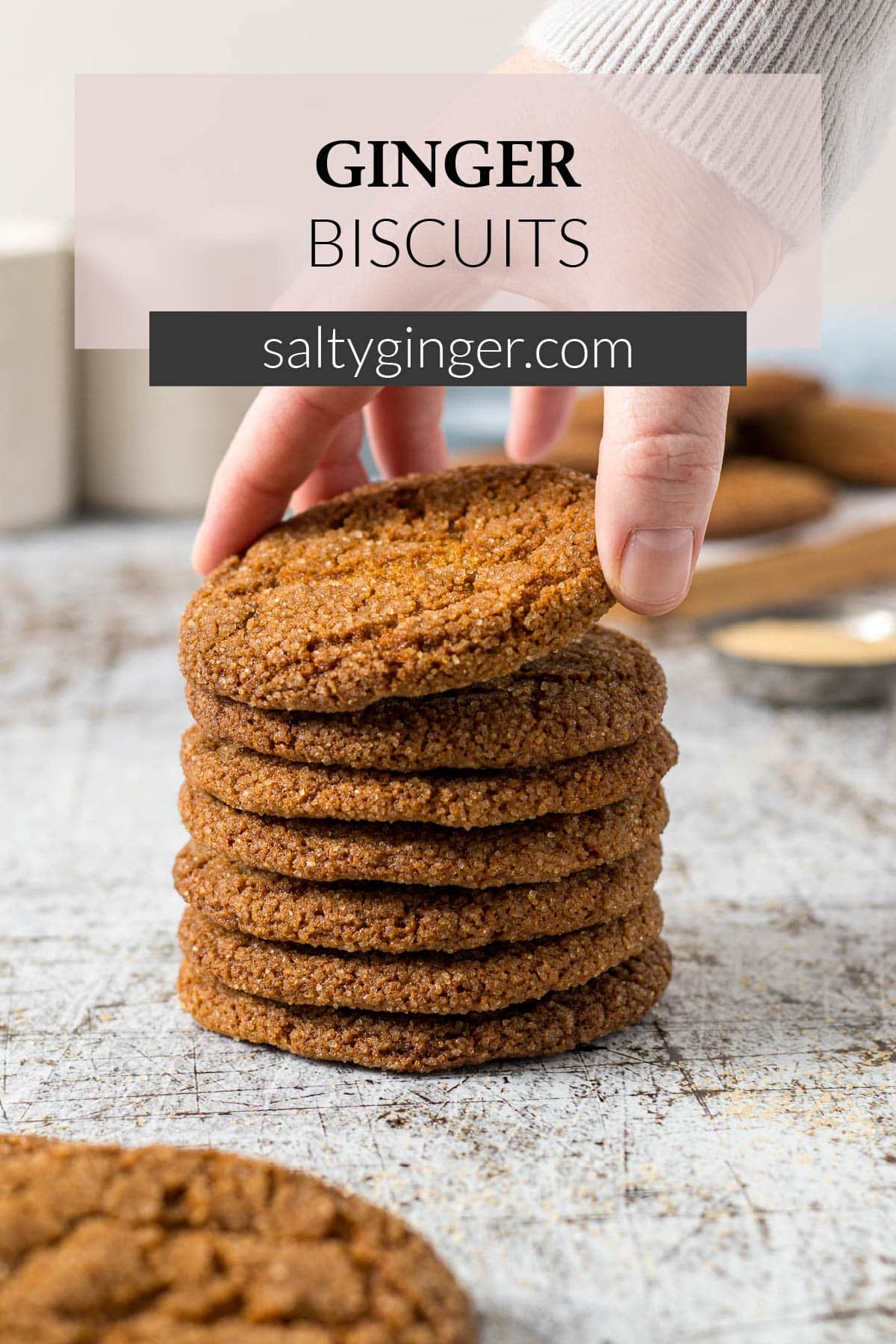 Pin - Hand picking up a ginger cookie off of a stack of cookies.