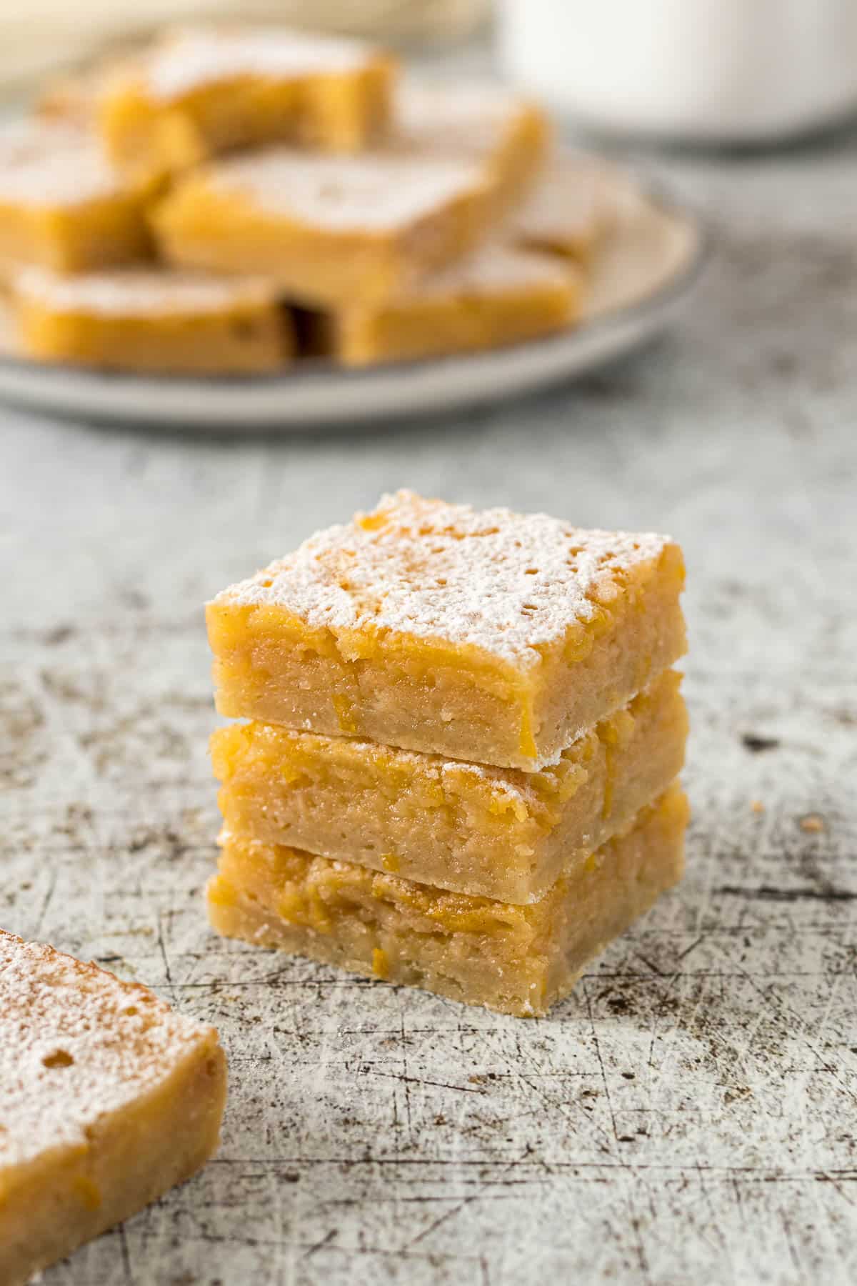 Three lemon bars stacked on each other with a dusting of icing sugar.