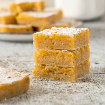 Three lemon bars stacked on each other with a dusting of icing sugar.