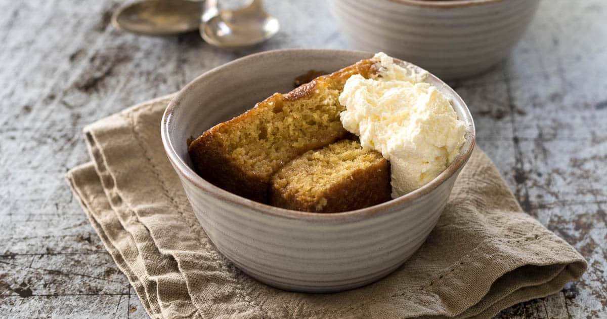Bowl of Malva pudding with some whipped cream in a bowl.