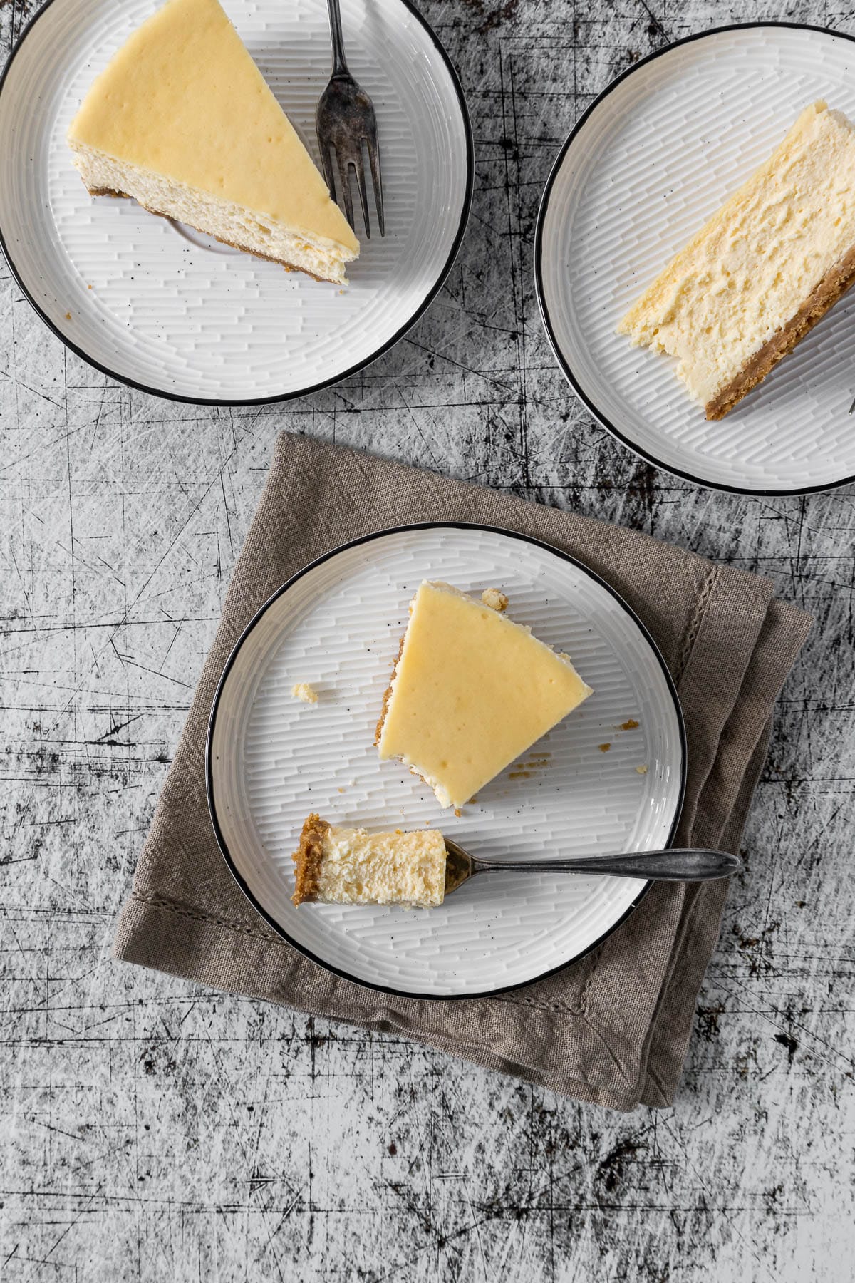 Slices of cheesecake on plates with cake forks.