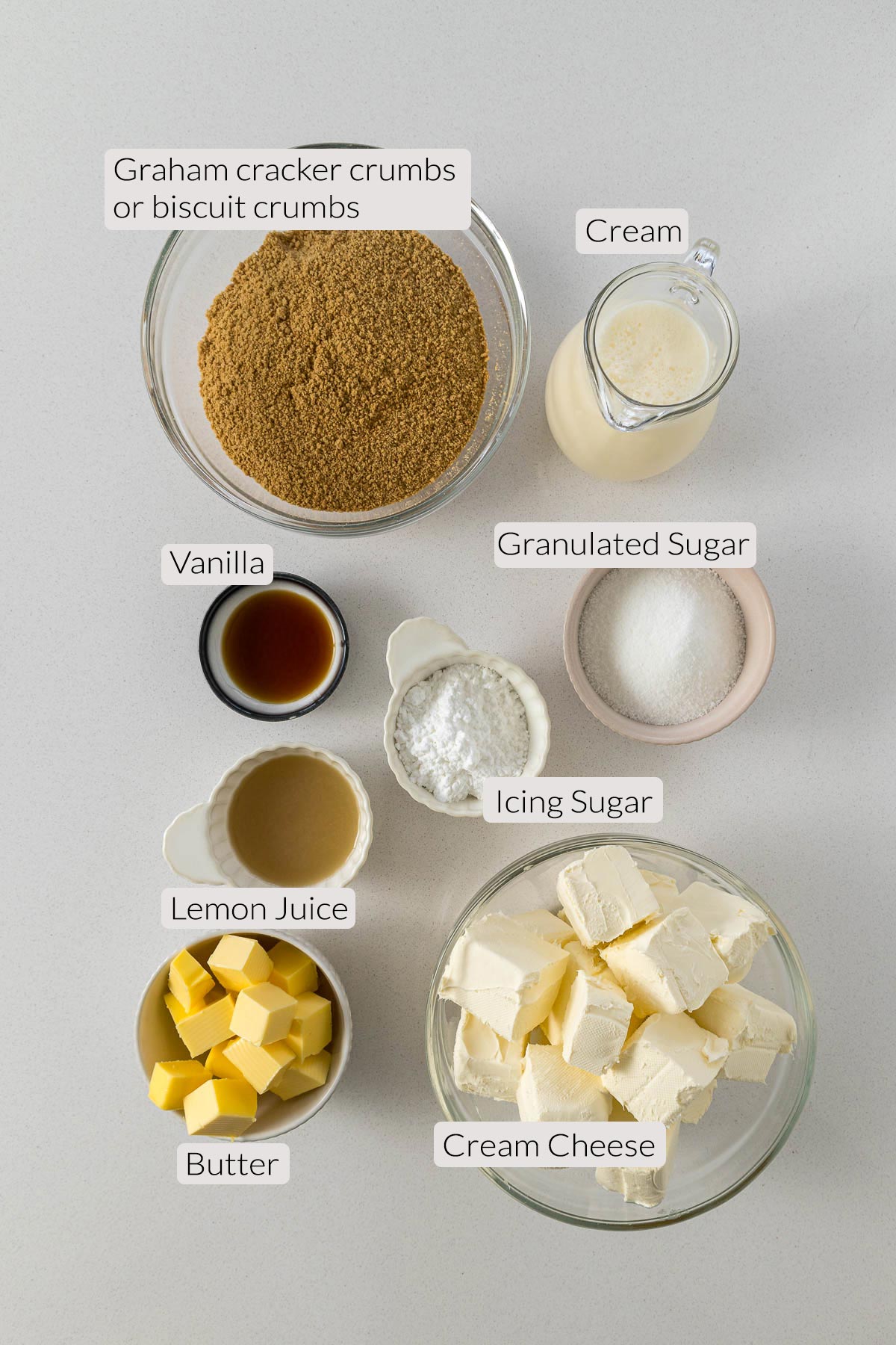 No-bake cheesecake ingredients - biscuit crumbs, cream, vanilla, lemon juice, white sugar, icing sugar, butter, and cream cheese.