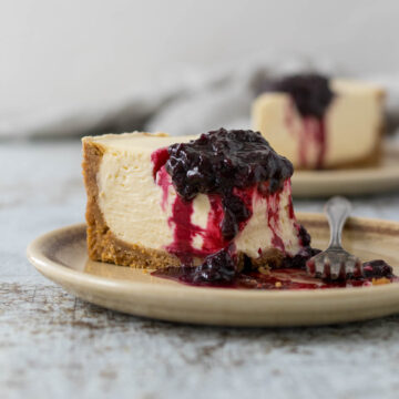 Slice of Philadelphia no-bake cheesecake on a plate with a berry compote.
