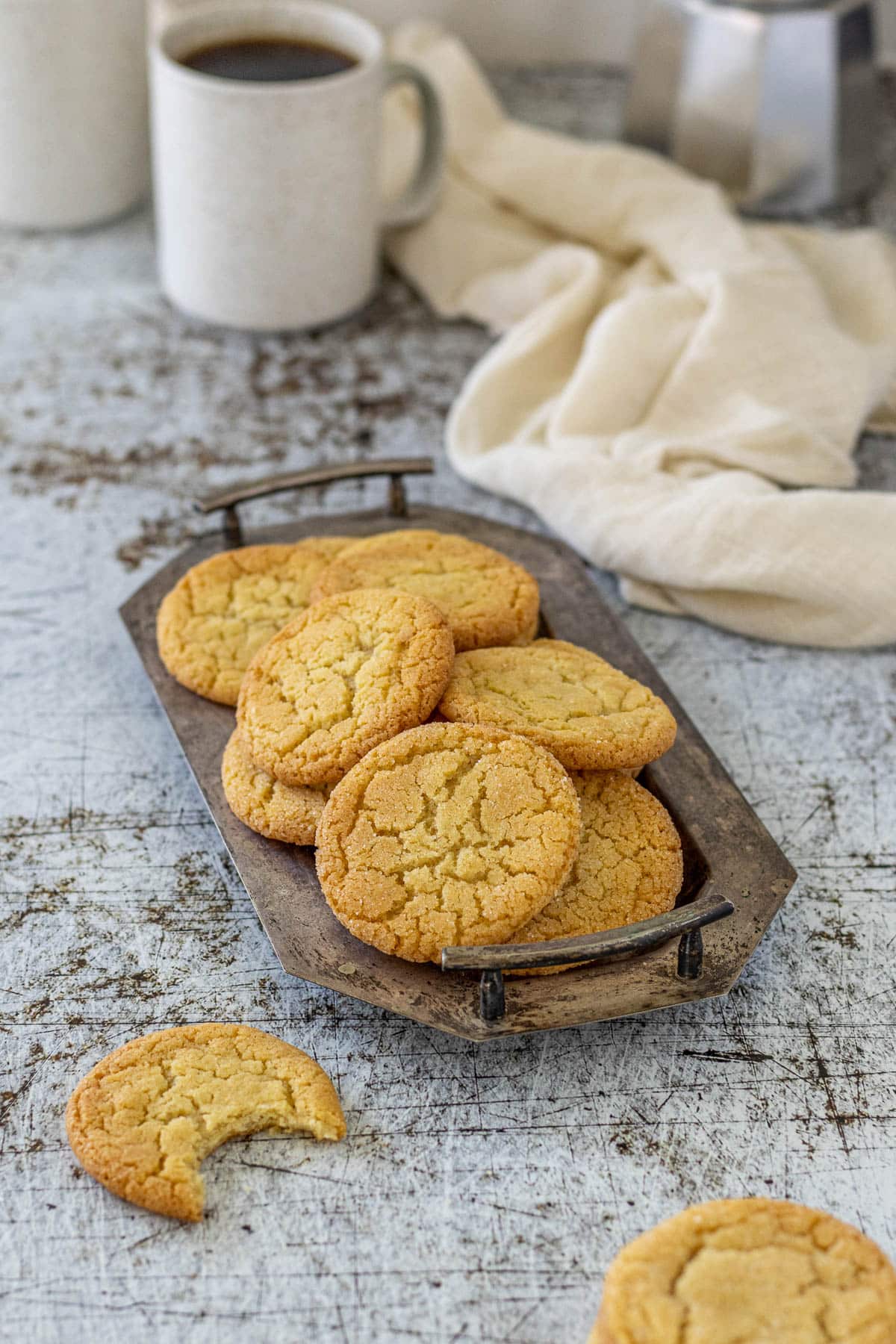 Vanilla sugar cookies in a serving dish with cups of coffee.