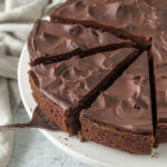 Sliced chocolate fudge cake on a cake stand.
