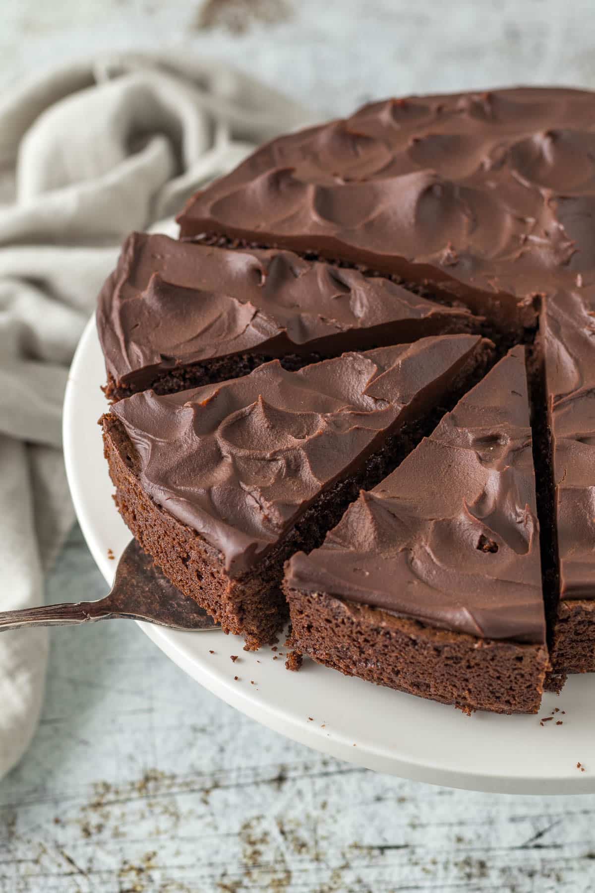 Sliced chocolate fudge cake on a cake stand.