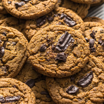 Chocolate chip espresso cookies on top of each other on a baking tray.