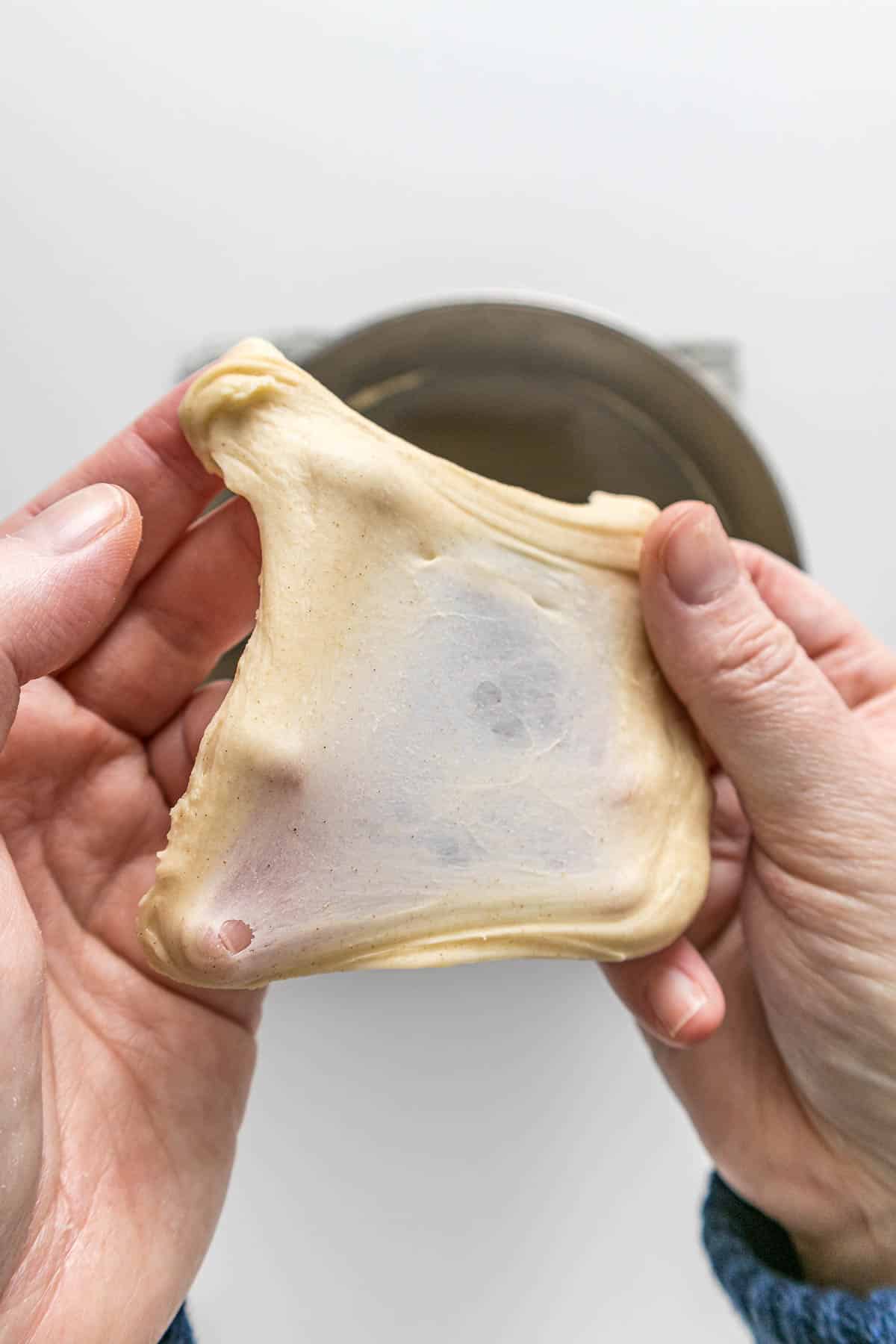 Step 4 - Bread dough stretched out between the fingers showing the window pane test.