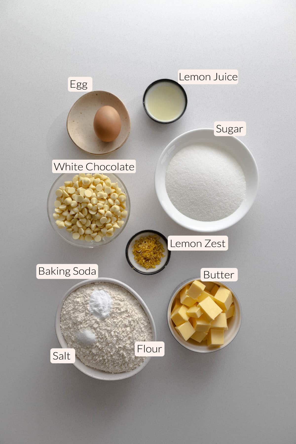 Lemon white chocolate cookie ingredients - egg, lemon juice, lemon zest, sugar, white chocolate chips, baking soda, salt, flour, and butter.