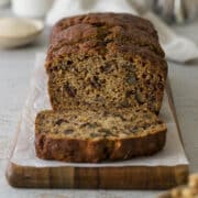Sliced banana date loaf on a wooden plate.